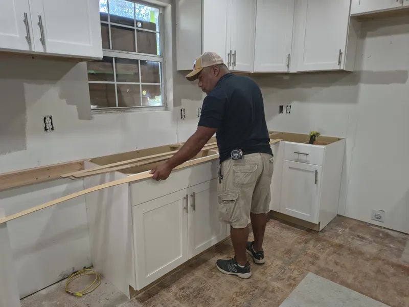 Fernando fitting thin wooden strips along new cabinets to build a template