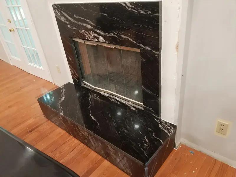 Black veined stone fireplace surround and raised hearth