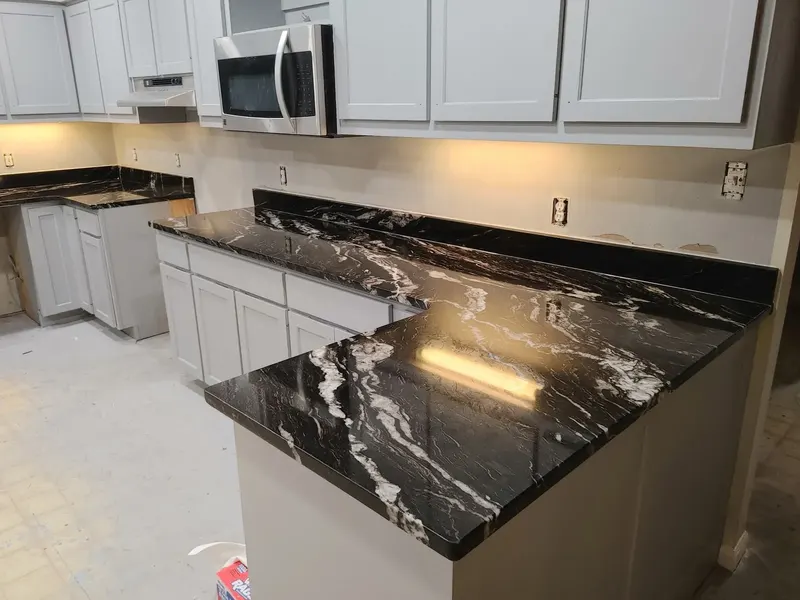 Black stone counters with white veins in an L shape over gray cabinets with under-cabinet lights