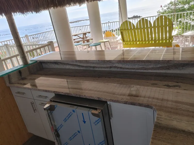 Long brown and gray veined stone bar on a covered deck overlooking the water