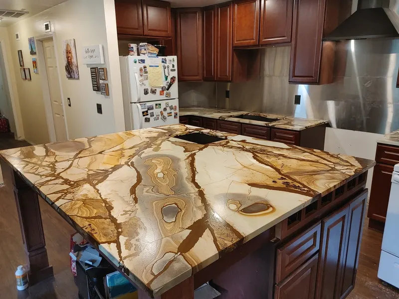 Cream stone island with bold gold veins over dark cherry cabinets