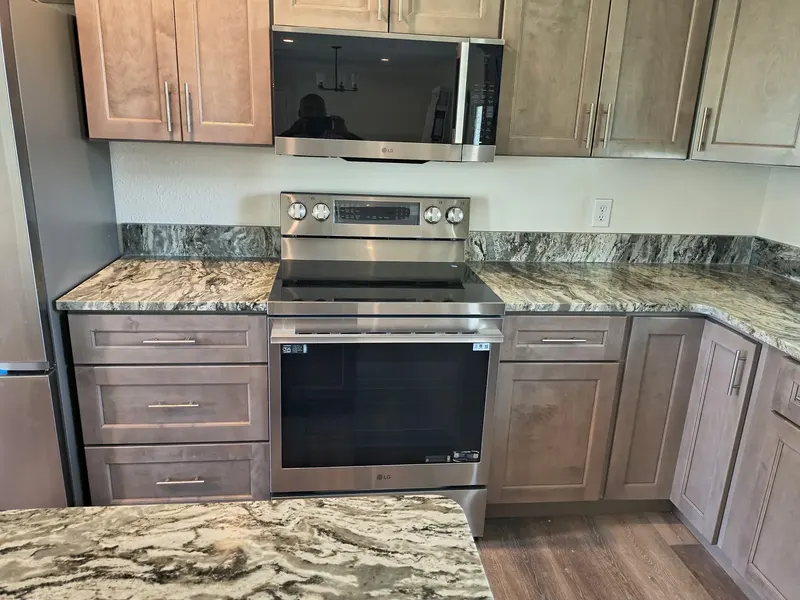 Gray and white swirled counter and backsplash around a stainless range with light brown cabinets
