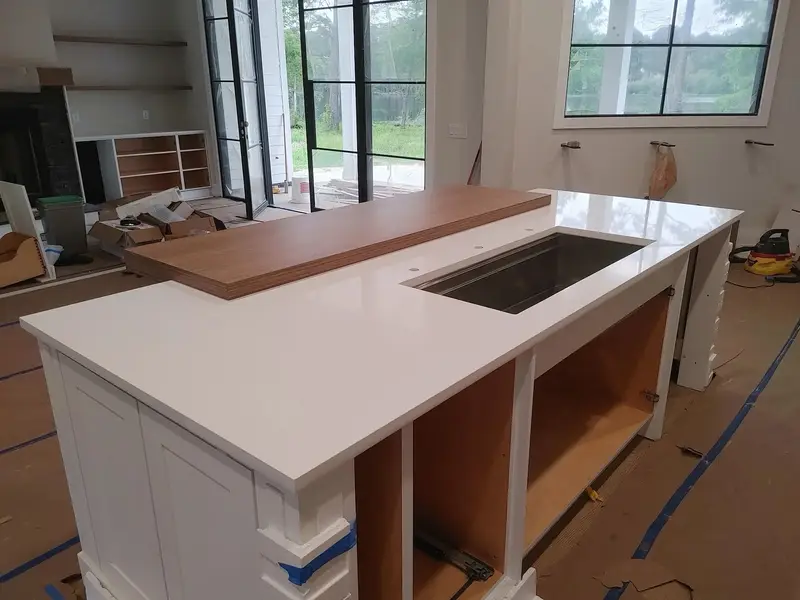 White stone island with an undermount sink and a raised wood bar top
