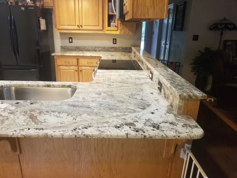 Light stone counter with brown and gray swirls and a raised bar ledge over oak cabinets