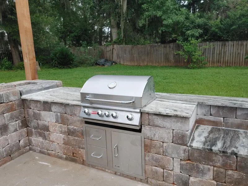 Gray and white veined stone tops on a brick paver grill station with a built-in stainless grill