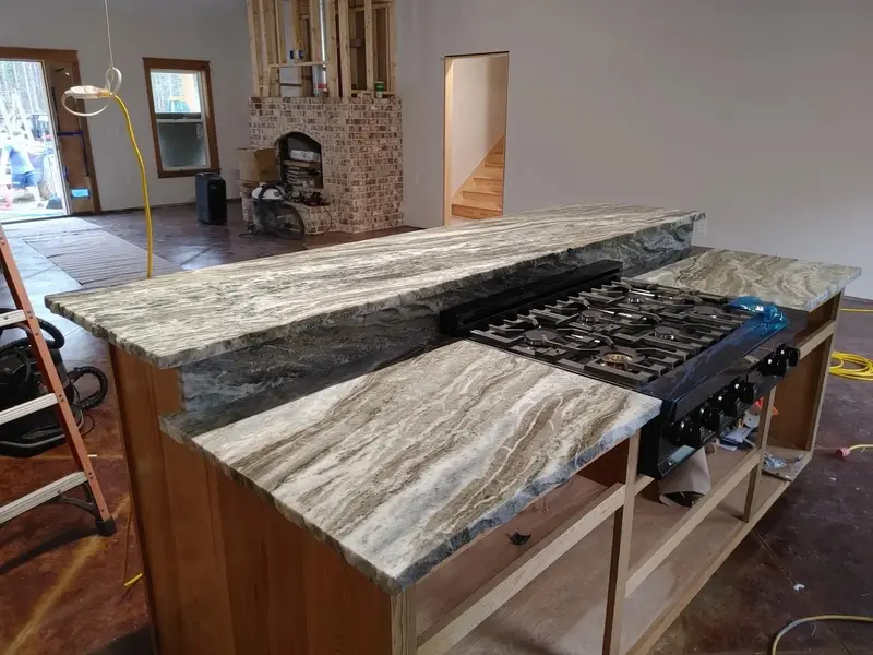 Two level gray veined stone island with a gas cooktop