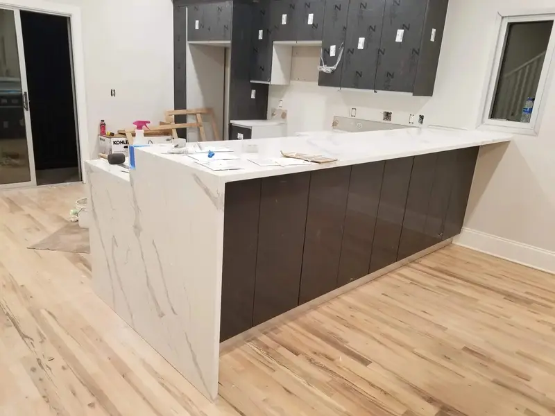 White veined stone island with waterfall ends over dark cabinets