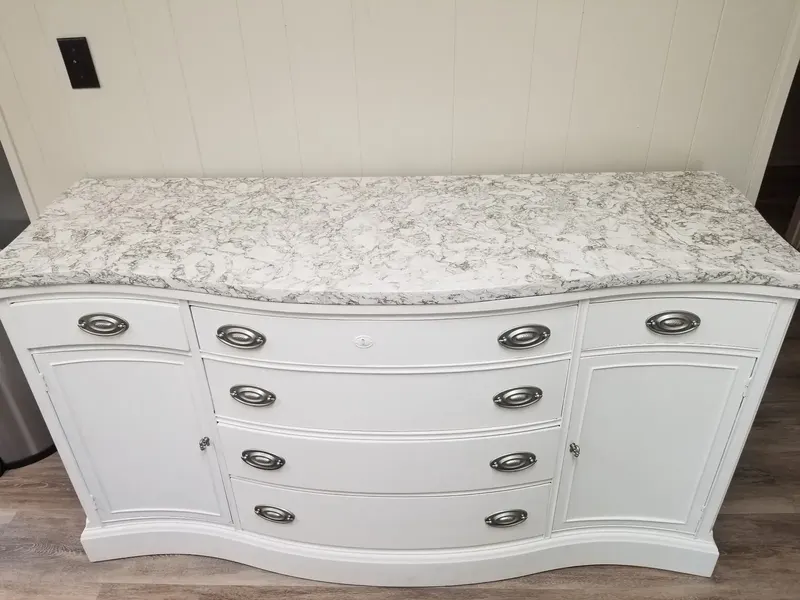 White buffet cabinet with silver pulls and a light gray and white speckled stone top