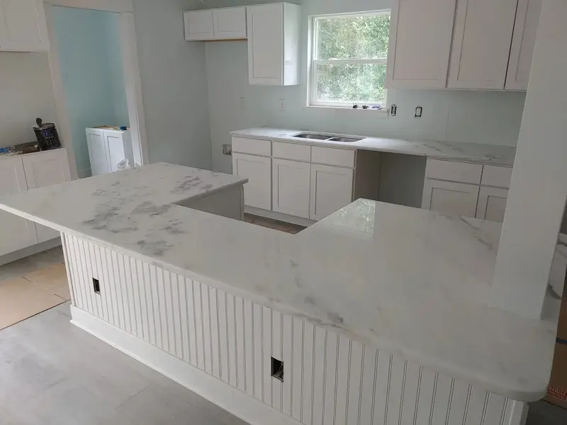 White veined stone island over beadboard cabinets